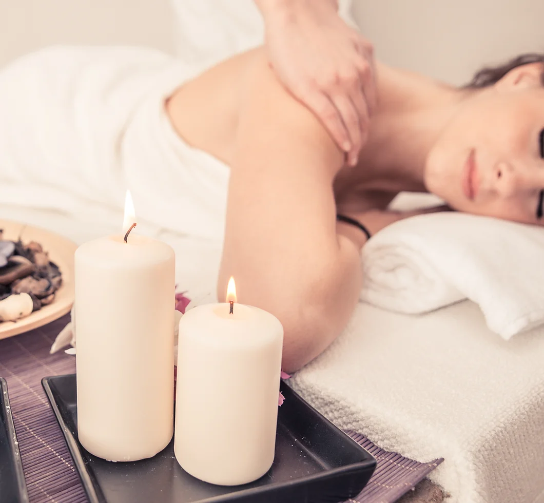 Woman on massage table with candles in the foreground